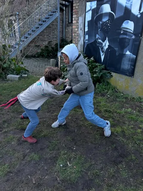 Twee jongens stoeien uitgelaten in een tuin.